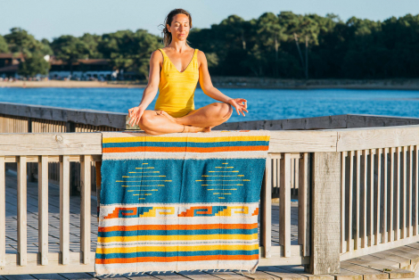 Ethnic blanket with woman in yellow swimming suit meditating on it