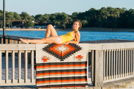 Ethnic blanket with woman in yellow swimming suit lying on it