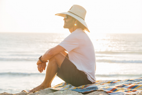 Man with straw hat at beach during sunset