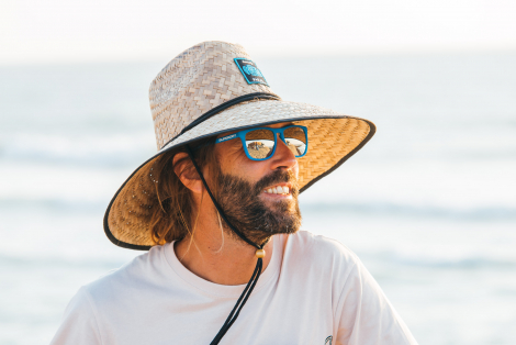 Man in straw hat and sunglasses looking at the ocean
