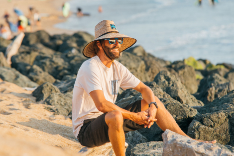 man watching the ocean with beach hat and sunglasses