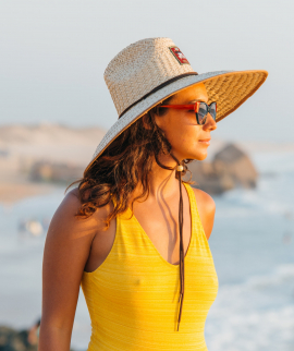 Women in yellow swimming suit and beach straw hat looking at the ocean
