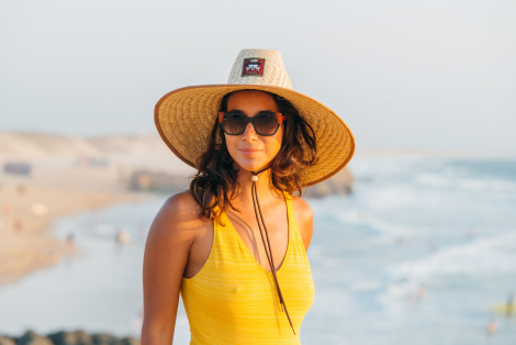 woman in yellow swimming suit and lifeguard hat smiling to the camera